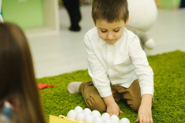 Los niños juegan con huevos de juguete en el jardín de infantes. Guardería. Niño y niñas — Foto de Stock