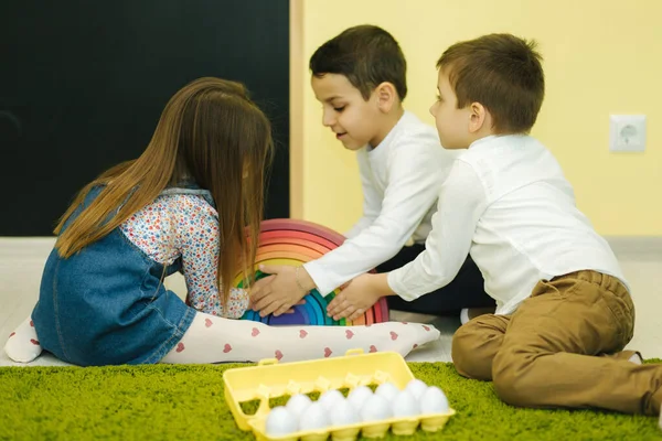 Los niños juegan con huevos de juguete en el jardín de infantes. Guardería. Niño y niñas — Foto de Stock