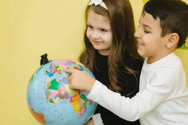 Niño con dos chicas mirar el mundo y buscar diferentes continentes y países — Foto de Stock