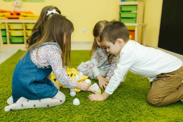 Dzieci bawią się jajkami w przedszkolu. Pokój dziecinny. Chłopiec i dziewczęta — Zdjęcie stockowe