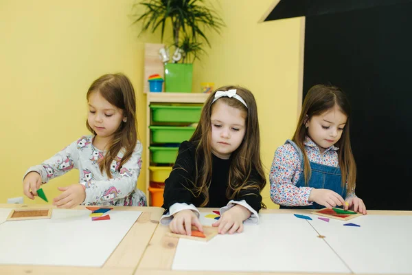 As crianças brincam com figuras diferentes na mesa. Meninas e meninos no jardim de infância — Fotografia de Stock