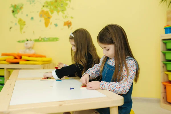 Los niños juegan con diferentes figuras sobre la mesa. Niñas y niños en el jardín de infancia — Foto de Stock