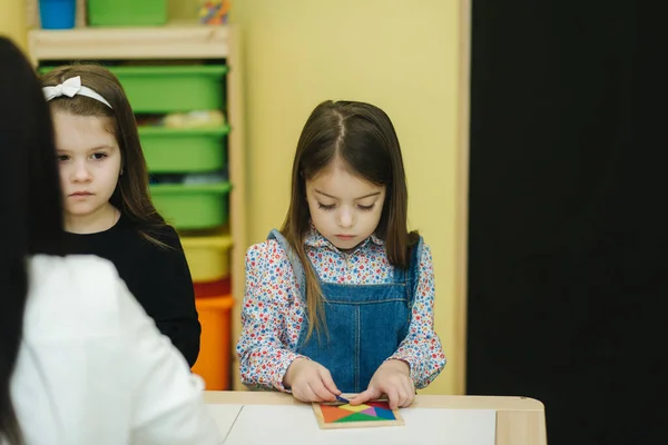 子供たちはテーブルの上でさまざまな数字で遊ぶ。幼稚園の女の子と男の子 — ストック写真