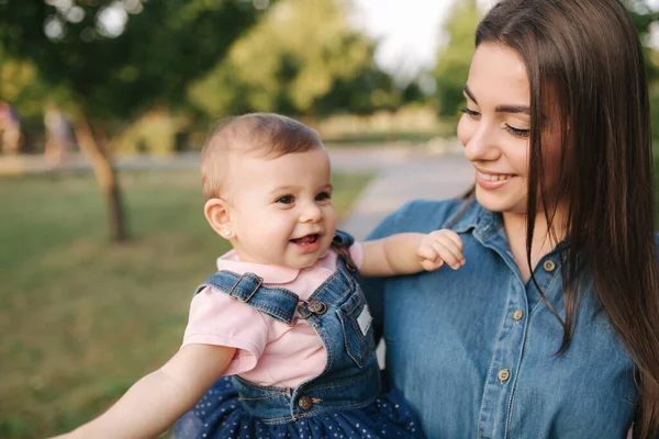 Copil drăguț pe mâinile mamelor afară. Familia în parc în timpul verii. Stilul Denim. Mama și fiica în blugi — Fotografie, imagine de stoc