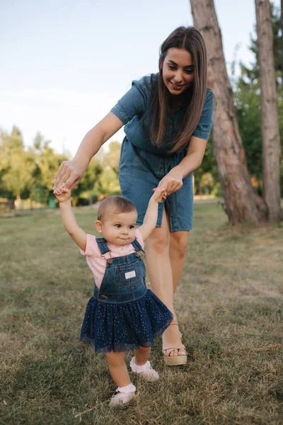 Az imádnivaló kislány első lépése a nyári parkban. Anya és lánya. — Stock Fotó