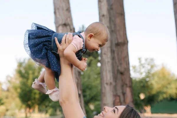 Słodkie dziecko na rękach mamy na zewnątrz. Rodzina w parku latem. W stylu dżinsów. Mama i córka w dżinsach — Zdjęcie stockowe