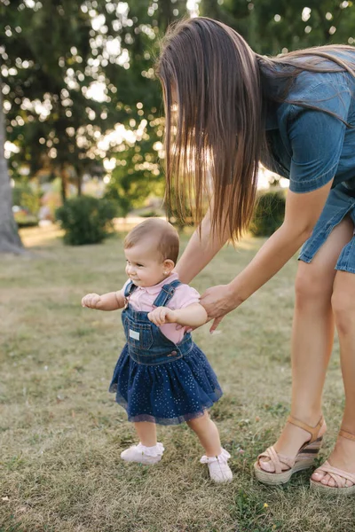 Första steget av bedårande liten flicka i sommarparken. Mamma och dotter går — Stockfoto