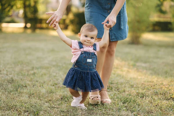Первый шаг очаровательной маленькой девочки в летнем парке. Мама и дочь идут — стоковое фото