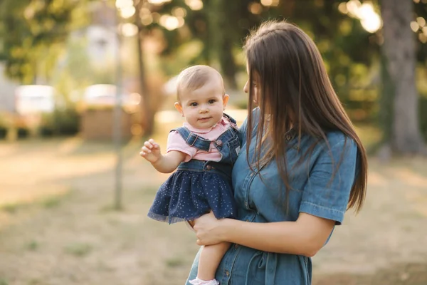 Cute baby girl walking with her mom and have fun. Stylish family. Mom and daughter in jeans