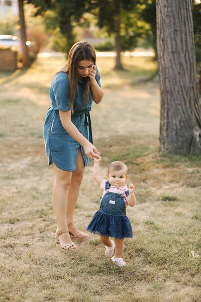 Första steget av bedårande liten flicka i sommarparken. Mamma och dotter — Stockfoto