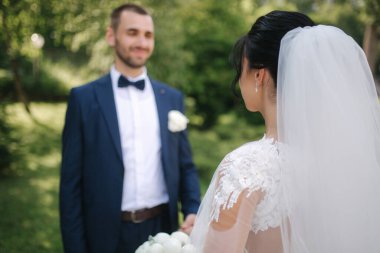 Güzel gelini ve yakışıklı damadı düğün gününde dışarıda yürüyor. Mutlu yeni evliler.