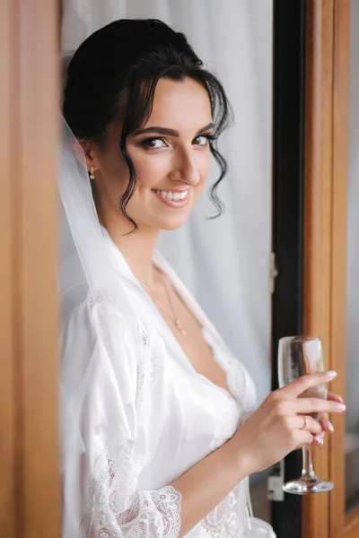 Retrato de novia hermosa con copa de champán en el hotel por la mañana. Encantadora mujer con gran peinado y maquillaje —  Fotos de Stock
