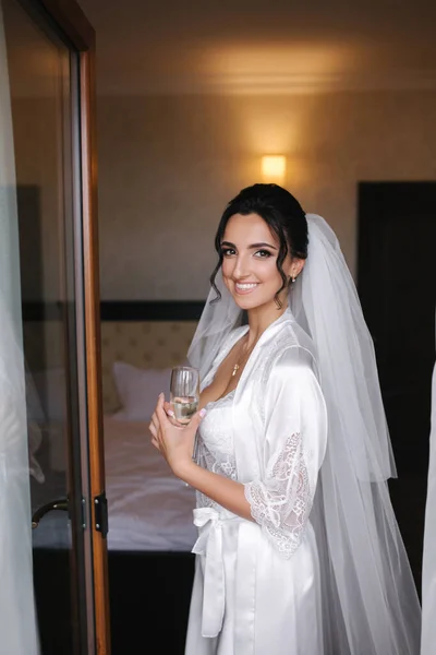 Retrato de novia hermosa con copa de champán en el hotel por la mañana. Encantadora mujer con gran peinado y maquillaje —  Fotos de Stock