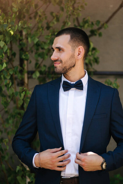 Portrait of handsome bearded groom in dark blue suit