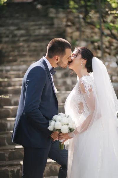 Mooie bruid met haar knappe bruidegom die buiten loopt op de trouwdag. Gelukkige pasgetrouwden — Stockfoto