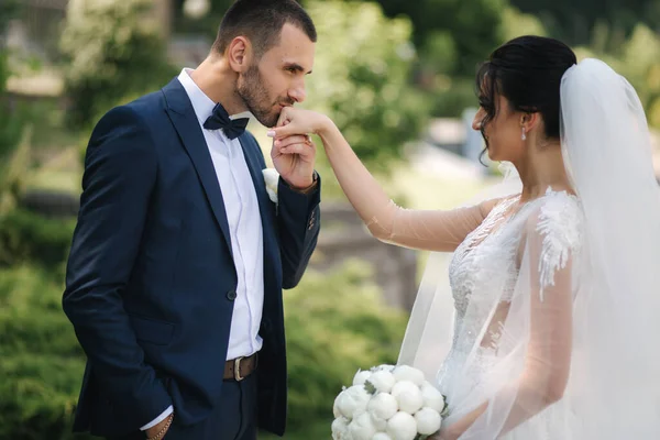 Güzel gelini ve yakışıklı damadı düğün gününde dışarıda yürüyor. Mutlu yeni evliler. — Stok fotoğraf