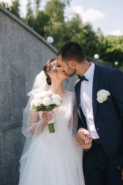 Schöne Braut mit ihrem hübschen Bräutigam, der am Hochzeitstag draußen spaziert. Glückliche Frischvermählte — Stockfoto