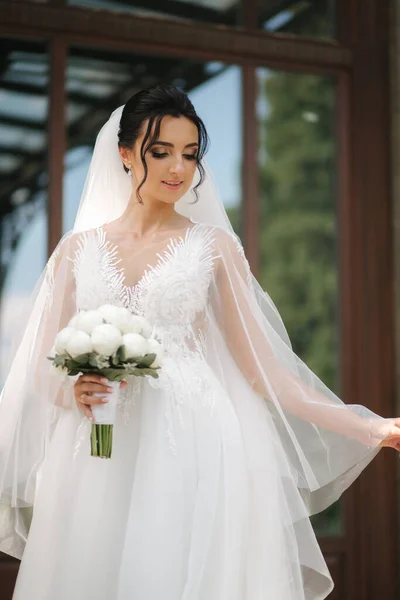 Linda noiva em vestido de noiva elegante com buquê de flores brancas em seu dia do casamento — Fotografia de Stock