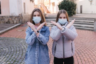 Maskeli kızlar. Coronavirus teması. Şehirdeki kadınlar karantina sırasında yürür. Kadın çapraz kollar