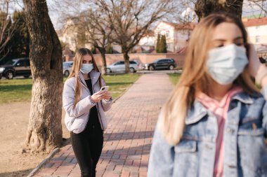 Maskeli kızlar. Coronavirus teması. Şehirdeki kadınlar karantina sırasında yürür. Kadın, ellerini yüzüne koy.