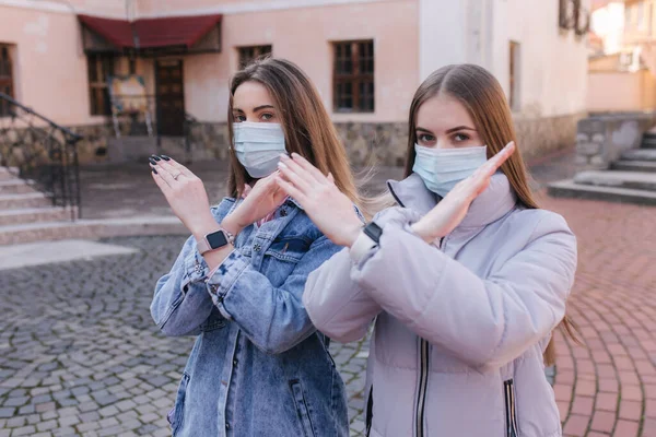 Maskeli kızlar. Coronavirus teması. Şehirdeki kadınlar karantina sırasında yürür. Kadın çapraz kollar