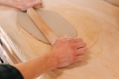 Erkek çömlekçi kil için rollong pin kullanır. Atölyedeki adam