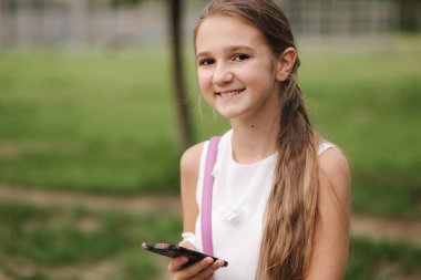 Genç kız okul tatilinde telefon kullanır. Kız çevrimiçi oyunlar oynuyor