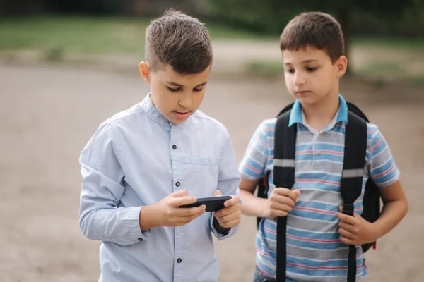 Två pojkar spelar onlinespel i karantän. Unga pojkar ler och använder telefonen — Stockfoto