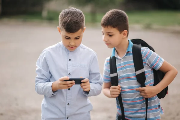Два хлопці грають в онлайн ігри на карантині. Молоді хлопці посміхаються і користуються телефоном — стокове фото