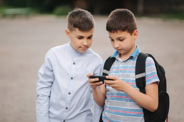 Två pojkar spelar onlinespel i karantän. Unga pojkar ler och använder telefonen — Stockfoto