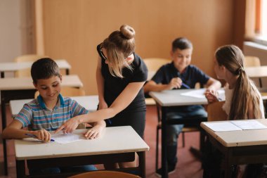 Öğretmenler sınıfta öğrencilerin yazma sınavına yardım ediyor. eğitim, ilkokul, öğrenim ve insanlar konsepti