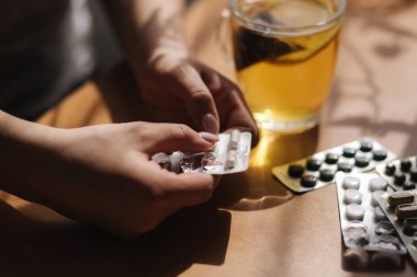 Kadın eli hapları yakın tut. Haplı el ve limonlu siyah çay. Dokunulmazlık. Vitaminler