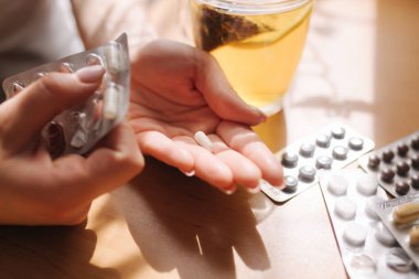 Kadın eli hapları yakın tut. Haplı el ve limonlu siyah çay. Dokunulmazlık. Vitaminler