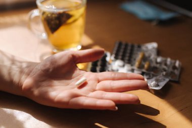 Kadın eli hapları yakın tut. Haplı el ve limonlu siyah çay. Dokunulmazlık. Vitaminler