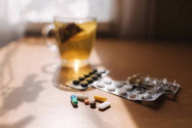 Masada bir sürü renkli hap ve çay var. Coronavirus konsepti
