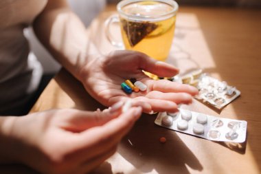 Kadın eli hapları yakın tut. Haplı el ve limonlu siyah çay. Dokunulmazlık. Vitaminler