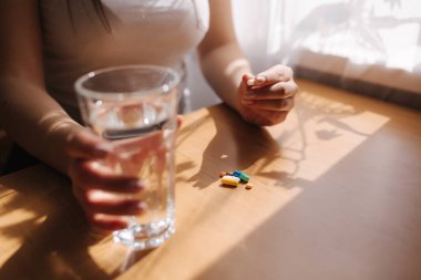 Kadın eli hapları yakın tut. Haplarla ve bir bardak suyla. Dokunulmazlık. Vitaminler