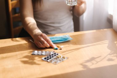 Kadın ilaç almak için maskesini çıkardı. Karantinada bir kadın var. Kendini soyutlama. Helthy kadın vitamin alıyor.