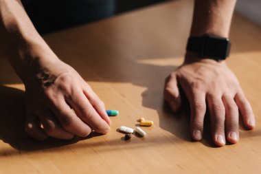 Erkeklerin ellerinde bir sürü renkli hap var. Elinde saat olan bir adam. Coronavirus konsepti