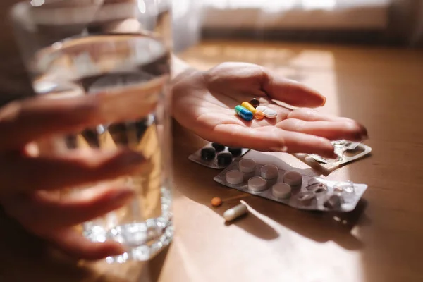 Großaufnahme von Frauenhänden mit Tabletten. Hand mit Tabletten und einem Glas Wasser. Immunität. Vitamine — Stockfoto