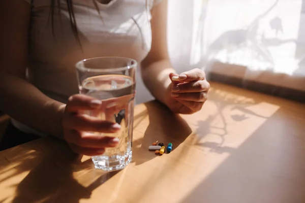 A női kezek közelről tartják a tablettákat. Kézzel pirulákkal és egy pohár vízzel. Védettség. Vitaminok — Stock Fotó