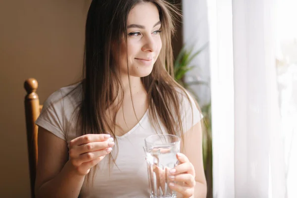Egy nő portréja, amint tablettákat eszik. Nő otthon a karanténban. Elszigeteltség. A segítőkész nő vitaminokat szed — Stock Fotó