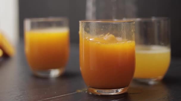 Close up ice drop in glass with orange juice. Slow motion — Stock Video