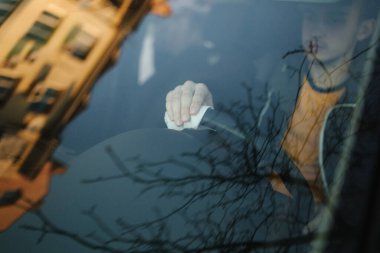 Adam ıslak mendil kullanarak direksiyonu temizliyor. Adam kendini ve temiz arabayı antiseptik kullanarak koruyor.