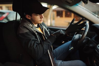 Arabadaki adam kendini korumak için siyah eldiven giydi.