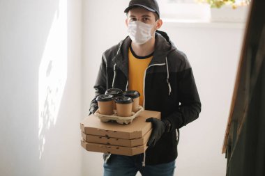 Maskeli ve eldivenli müşterilere pizza ve kahve getiren adam. Coronavirus teması