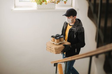 Maskeli ve eldivenli müşterilere pizza ve kahve getiren adam. Coronavirus teması