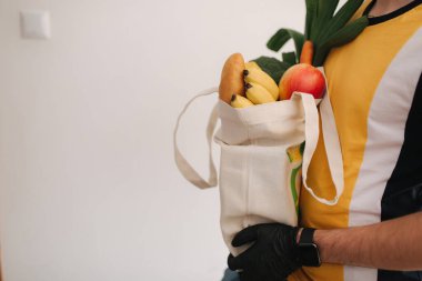 Maskeli ve eldivenli teslimatçı müşterilere taze yiyecek getiriyor. Evde kal. Çevrimiçi alışveriş kavramı