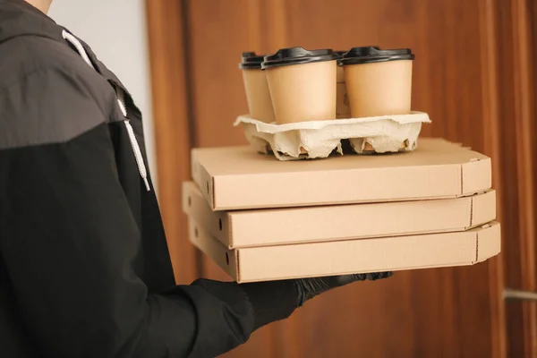 Närbild av människan hålla träd lådor med pizza. Människan levererar mat och kaffe till kunden i mask och handskar. Tema för Coronavirus — Stockfoto