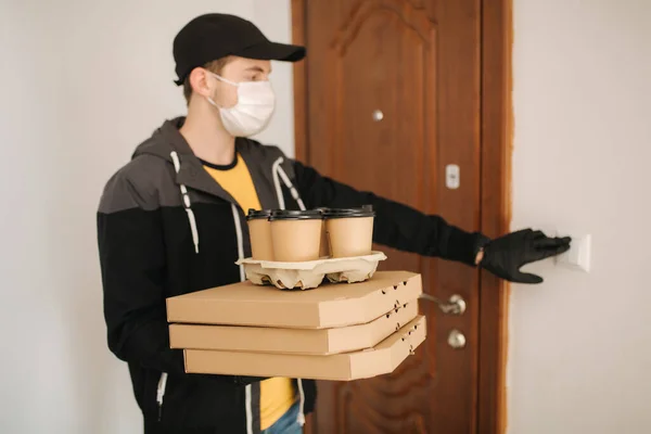 Man leverans pizza och kaffe till kund i mask och handskar. Coronavirus tema. Man ringer på dörren — Stockfoto